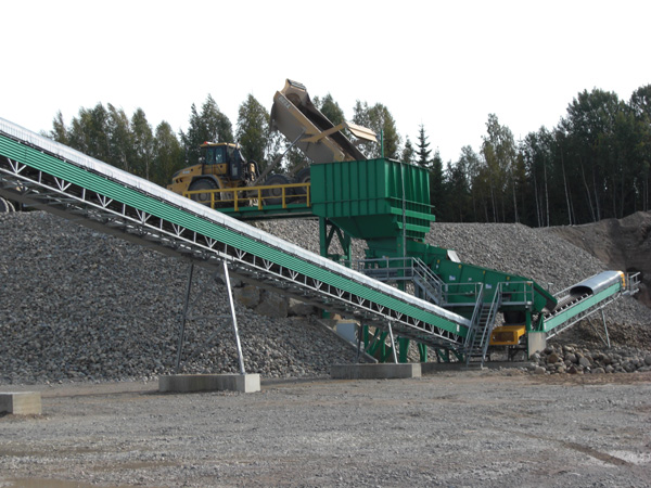 Transportband och dumper som tippar i krossen.