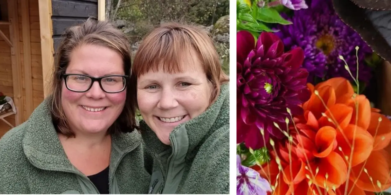 Två personer i gröna tröjor står framför ett träskjul; till höger syns färgglada blommor.