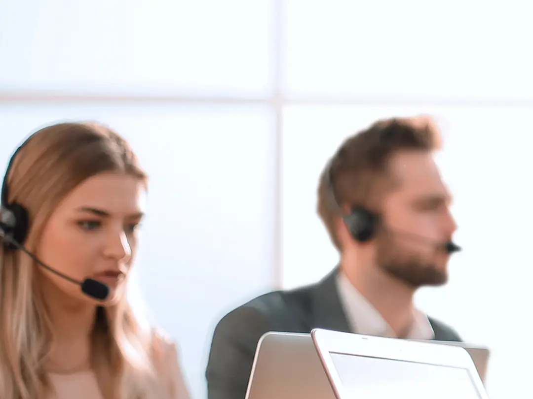 Mitarbeiter in einem modernen Büro arbeiten mit Headsets und Computern.