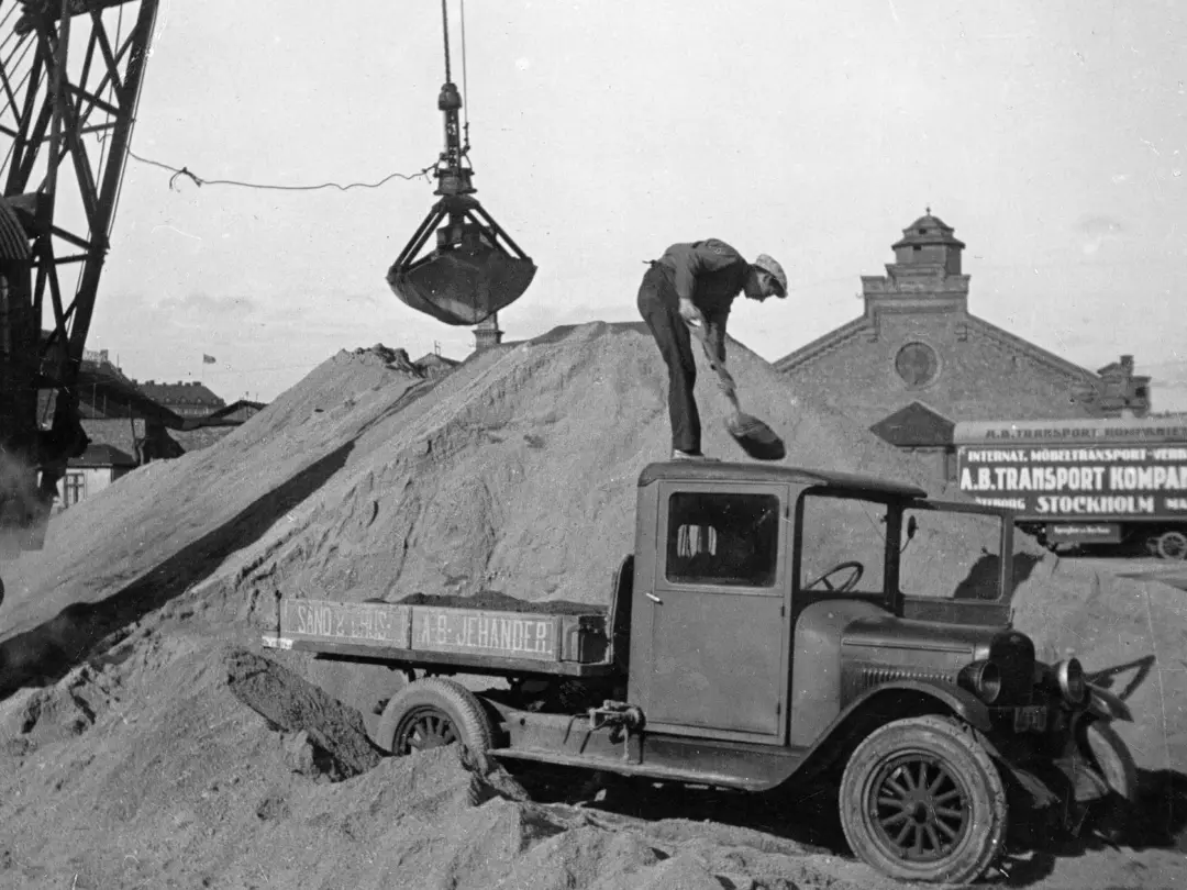Historisk bild med en man som lassar sand från ett lastbilsflak